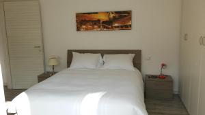 - un grand lit blanc dans une chambre avec une photo sur le mur dans l'établissement Appartamento Miro, à San Pellegrino Terme
