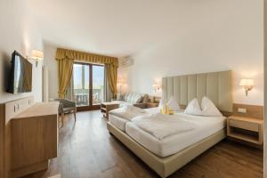 a hotel room with a large bed and a television at Hotel Förstlerhof in Postal