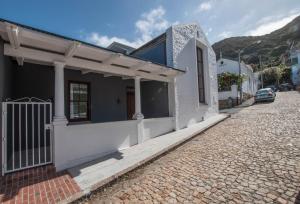 a white house on a cobblestone street at Rosmead Apartment in Kalk Bay