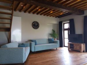 a living room with blue couches and a clock on the wall at Logies Berckelaer in Sint-Gillis-Waas