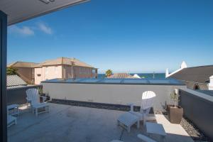 a patio with two chairs and a white boat on a roof at Rosmead Apartment in Kalk Bay