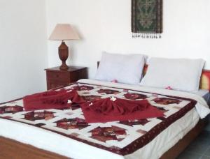 a bed with a red and white quilt on it at Nuriani Guest House in Ubud