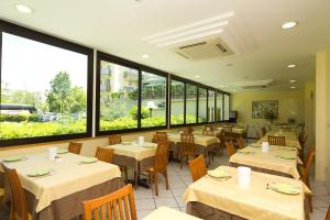 a restaurant with tables and chairs and large windows at Hotel Pigalle in Riccione