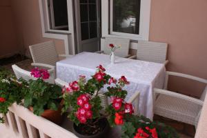 una mesa con flores rojas y sillas en Apartments Tanja & Josipa, en Pag