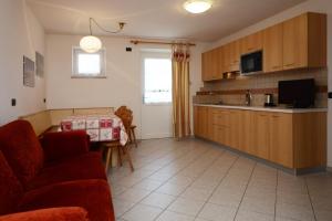 a living room with a red couch and a kitchen at Residence Ciasa Alpe in Vigo di Fassa