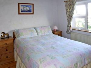 ein Schlafzimmer mit einem Bett, einer Kommode und einem Fenster in der Unterkunft Delia's Cottage in Ballinrobe