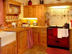 a kitchen with wooden cabinets and a red stove top oven at Fehanaugh Cottage in Atadav Bridge