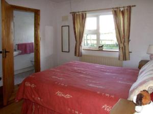 a bedroom with a red bed and a window at Delia's Cottage in Ballinrobe +2 photos
