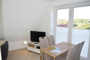 a dining room with a table and a television at Dünenmeer in Juist