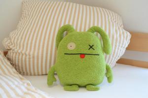um brinquedo de peluche verde está sentado numa cama em Dünenmeer em Juist