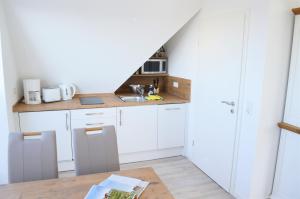 uma cozinha com armários brancos e uma bancada em Dünenmeer em Juist