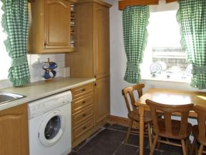 a kitchen with a washing machine and a table with chairs at Delia's Cottage in Ballinrobe