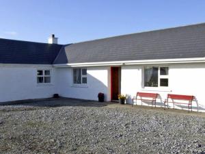 a white house with two red benches in front of it at Delia's Cottage in Ballinrobe