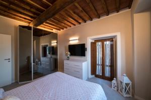 1 dormitorio con 1 cama blanca y TV en Rocca Palazzaccio, en Impruneta