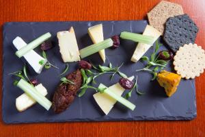 a blue plate with cheese and meats and vegetables at The Cobbles Inn Apartment in Kelso