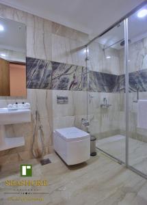 a bathroom with a shower and a toilet and a sink at Seashore Residency in Kodungallūr