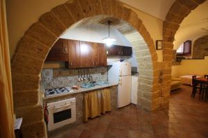 cocina con arco de piedra, fogones y nevera en Casa Porto Salvo, en Cefalú