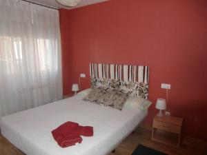 a bedroom with a white bed with red walls at Apartamento DH in Zamora