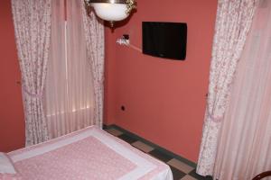Habitación con pared roja, TV y cortinas. en Hotel Frijon, en Aceuchal