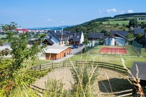 un groupe de maisons avec un court de tennis dans un champ dans l'établissement Wellness Pension & Salaš Šariš Park, à Prešov