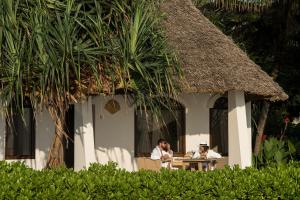two people sitting at a table in front of a hut at Essque Zalu Zanzibar in Nungwi