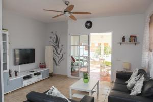 a living room with a couch and a flat screen tv at Villa Musica in Caleta De Fuste