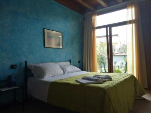Un dormitorio con una cama con paredes azules y una ventana en B&B Il Rondò Sirmione, en Sirmione