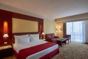 a hotel room with a large bed and a chair at Safir Hotel Cairo in Cairo