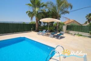 a swimming pool with two chairs and an umbrella at Villa Oasis in El Vendrell