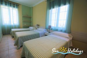 a group of three beds in a room with windows at Villa Oasis in El Vendrell +28 photos