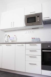 La cuisine est équipée de placards blancs et d'un four micro-ondes. dans l'établissement Apartmán U Prazdroje, à Plzeň