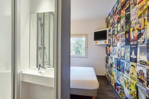 a bathroom with a bed and a sink and a mirror at hotelF1 Chartres in Le Coudray