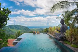 a pool at a resort with a statue in the water at Bella Kita Mountain Retreat & Spa in Klungkung