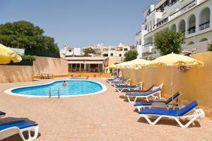 uma piscina com espreguiçadeiras e guarda-sóis em Apartamentos Do Parque em Albufeira