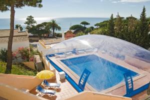 a house with a swimming pool and an umbrella at Apartamentos Do Parque in Albufeira