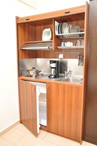 eine Küche mit Holzschränken, Spüle und Geschirr in der Unterkunft Al Mare in Asprovalta