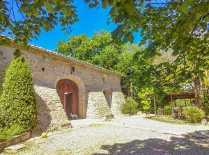 - un bâtiment en pierre avec une porte et un arbre dans l'établissement La Bastide De Sauvetas, à Bonlieu-sur-Roubion