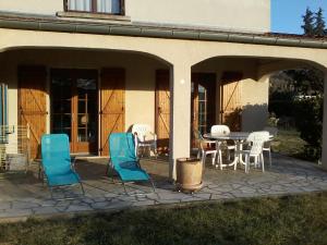 eine Terrasse mit blauen Stühlen sowie einem Tisch und Stühlen in der Unterkunft gîte en sud Ardèche in Ruoms