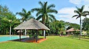 une cabane avec une table et des chaises à côté d'une piscine dans l'établissement Elephant Walk Retreat, à Komatipoort