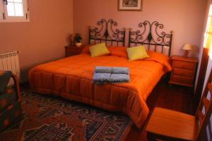 1 dormitorio con 1 cama con sábanas de color naranja y almohadas amarillas en Casa rural agro da moa en As Mirans