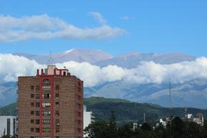 un edificio alto de ladrillo con montañas en el fondo en Temporarios B & B en San Salvador de Jujuy