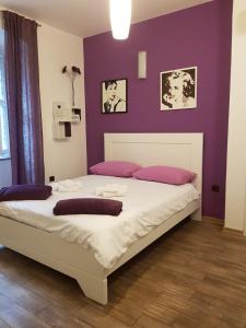 1 dormitorio con 1 cama grande y paredes moradas en Studios S, en Zadar