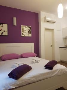 1 cama con 2 almohadas y pared púrpura en Studios S, en Zadar