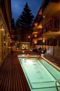 two people swimming in a swimming pool at night at Banff Aspen Lodge in Banff