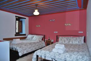 two beds in a room with red walls at Tritoxo Guesthouse in Koukouli