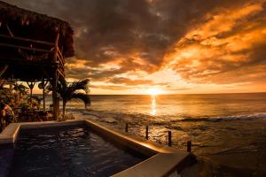 a swimming pool on the beach at sunset at Miramar SurfCamp in Puerto Sandino