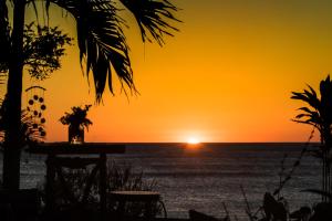 puesta de sol en la playa con mesa y sillas en Miramar SurfCamp en Puerto Sandino