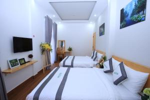a bedroom with two beds and a flat screen tv at Moc Tra Hotel in Da Lat