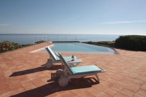 two lounge chairs and a pool on a brick patio at Dammusi I Jardina in Pantelleria