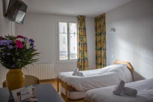 サン・テティエンヌ・ド・ティネにあるLe Rabuonsのベッド2台と花のテーブルが備わる客室です。